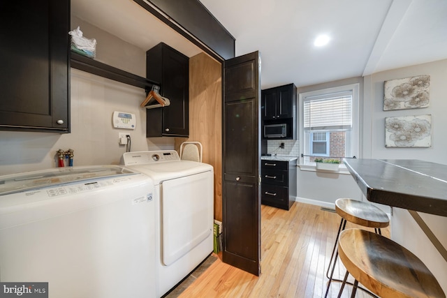 laundry room featuring cabinet space, light wood-style floors, and independent washer and dryer