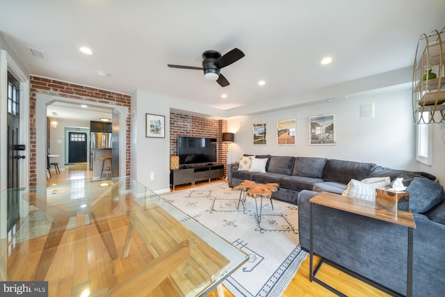 living area featuring visible vents, recessed lighting, brick wall, and wood finished floors