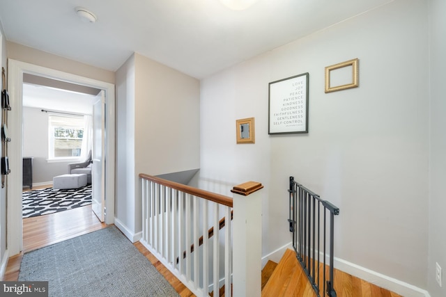 hall featuring baseboards, an upstairs landing, and light wood finished floors