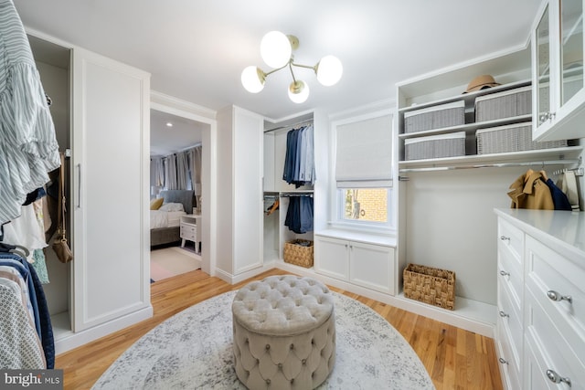 walk in closet featuring a chandelier and light wood finished floors