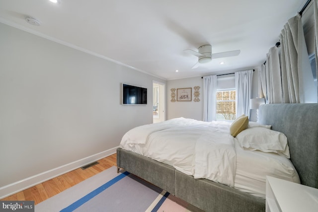 bedroom featuring a ceiling fan, wood finished floors, visible vents, baseboards, and ornamental molding