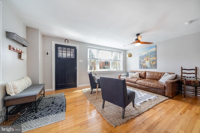 living room with baseboards, a ceiling fan, and light wood-style floors