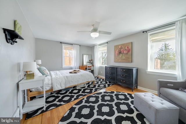 bedroom featuring a ceiling fan, baseboards, and wood finished floors