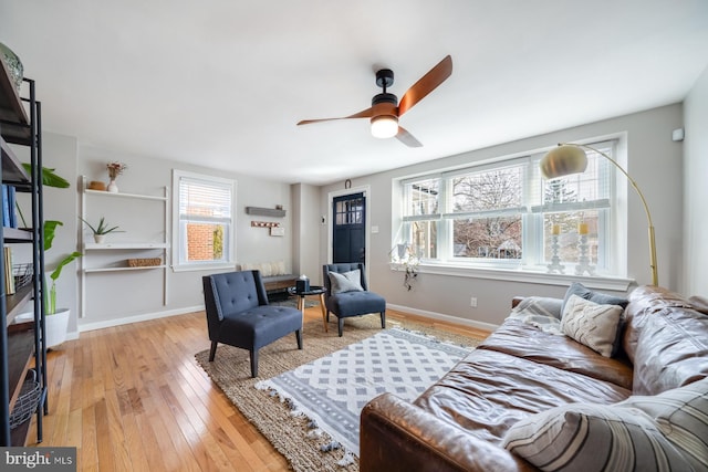 living area with baseboards, light wood-style floors, and ceiling fan