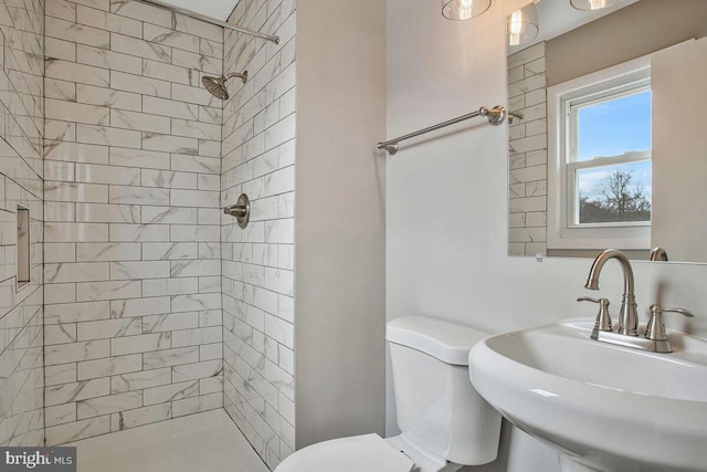 full bathroom featuring toilet, a sink, and tiled shower