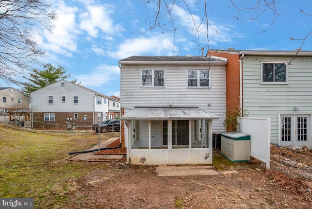 back of property with french doors, a lawn, fence, and a sunroom