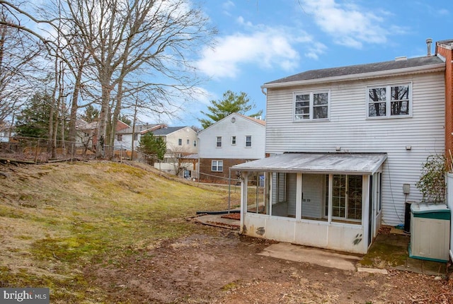 back of house featuring a yard, fence, and a sunroom