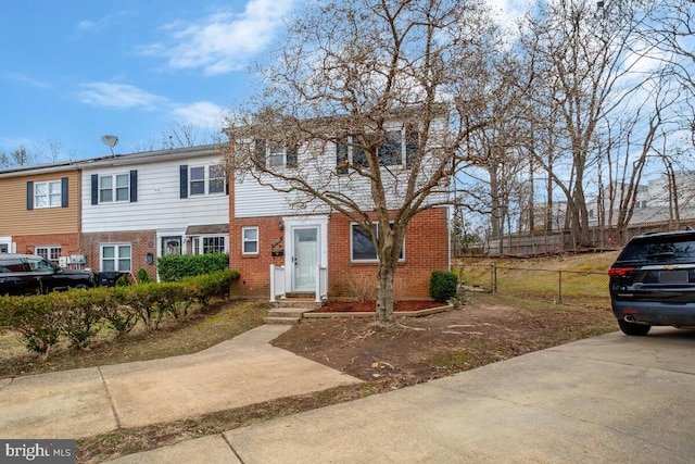 view of property featuring brick siding and fence