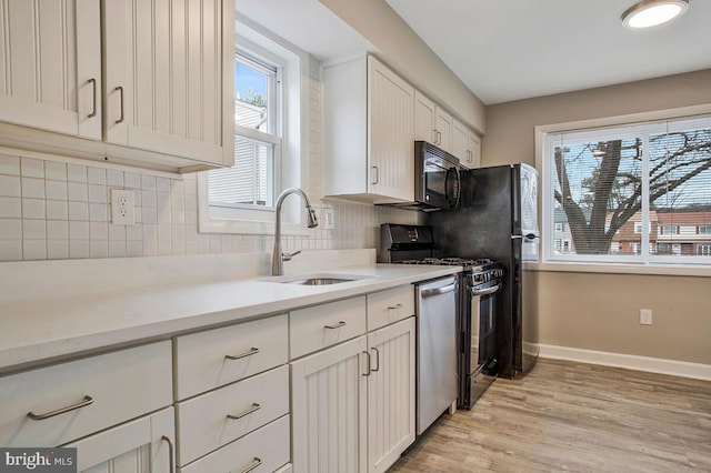 kitchen with decorative backsplash, dishwasher, range with gas cooktop, light wood-style floors, and a sink