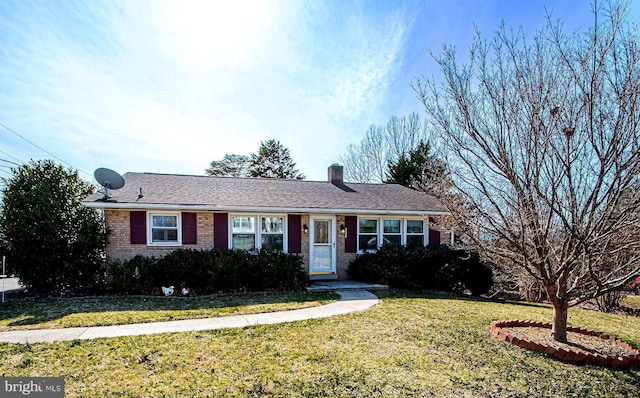 single story home with brick siding, a chimney, and a front yard