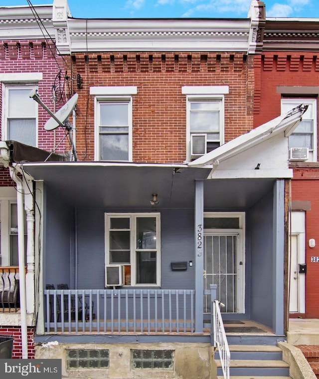 view of property featuring a porch and brick siding