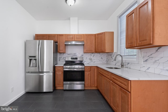 kitchen with under cabinet range hood, stainless steel appliances, a sink, light countertops, and decorative backsplash