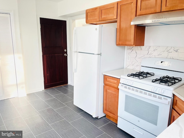 kitchen with white appliances, under cabinet range hood, and light countertops