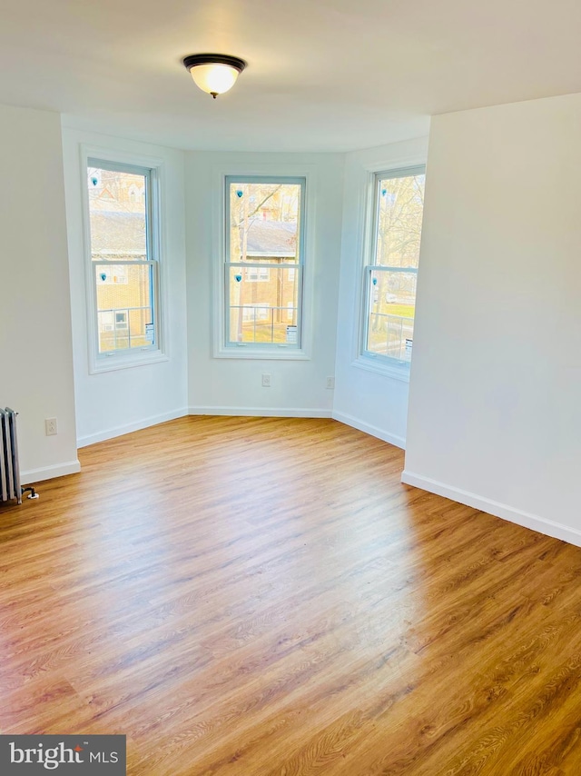 empty room featuring radiator, baseboards, and wood finished floors