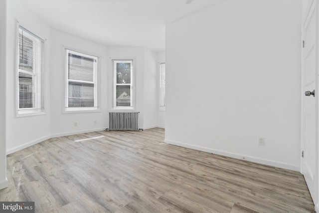 spare room with light wood finished floors, radiator heating unit, and baseboards