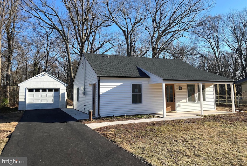 ranch-style home featuring a garage, a shingled roof, an outdoor structure, and aphalt driveway