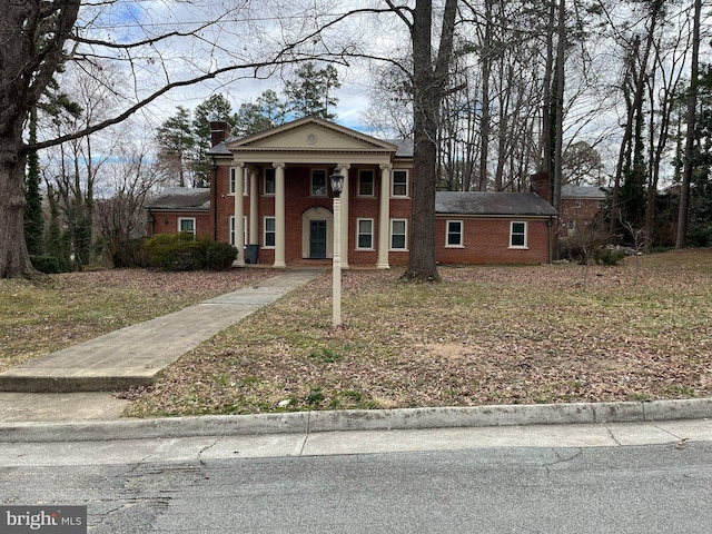 greek revival inspired property with brick siding and a chimney