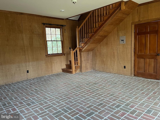 empty room featuring stairway, brick floor, and wooden walls