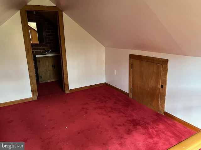 bonus room featuring baseboards, vaulted ceiling, and dark colored carpet