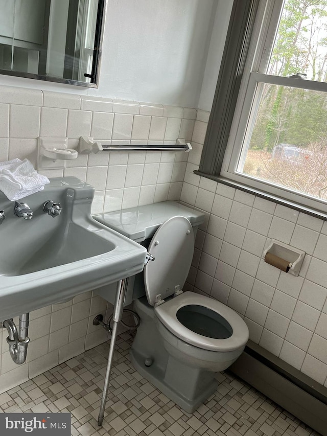 half bathroom featuring a baseboard radiator, tile walls, toilet, and tile patterned floors