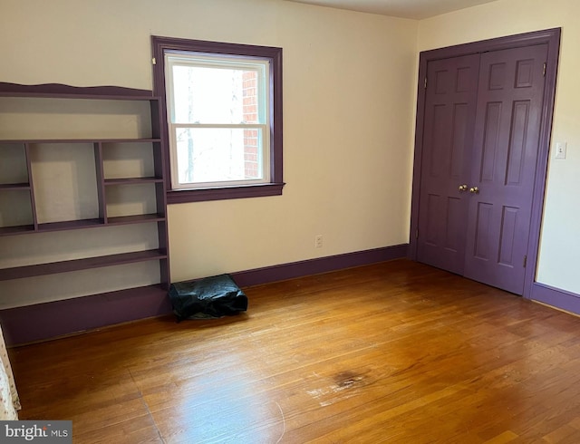 unfurnished bedroom featuring a closet, baseboards, and wood finished floors