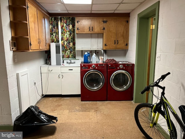 laundry room with light floors, separate washer and dryer, cabinet space, and concrete block wall