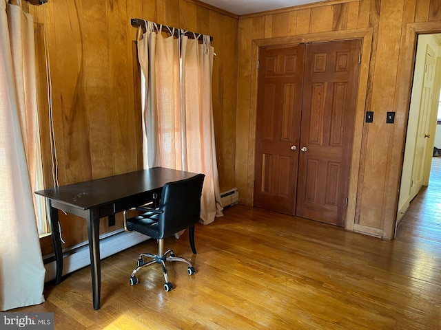 home office featuring light wood-style flooring, a baseboard radiator, and wooden walls