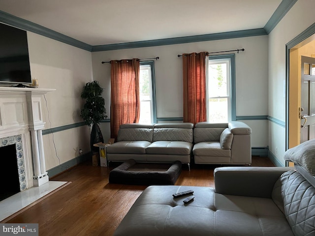 living room with a baseboard heating unit, wood finished floors, a fireplace, and ornamental molding