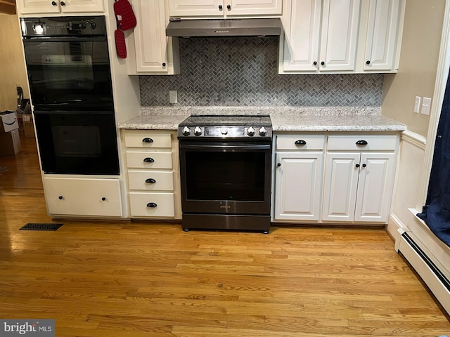 kitchen with a baseboard radiator, under cabinet range hood, dobule oven black, electric range oven, and light wood finished floors