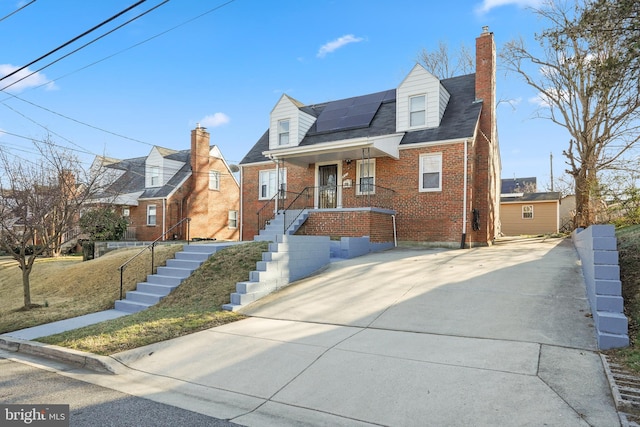 new england style home with brick siding, solar panels, and a chimney