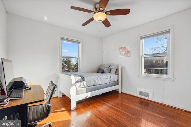 bedroom featuring visible vents, multiple windows, a ceiling fan, and wood-type flooring