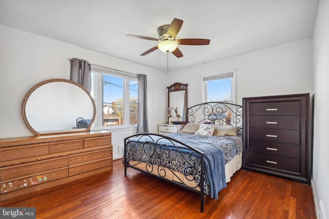 bedroom featuring ceiling fan, multiple windows, and dark wood-style floors