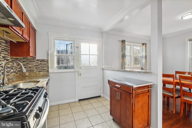 kitchen with under cabinet range hood, backsplash, light tile patterned flooring, and crown molding