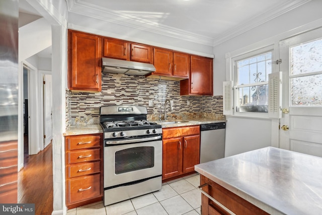 kitchen featuring under cabinet range hood, a sink, backsplash, appliances with stainless steel finishes, and crown molding