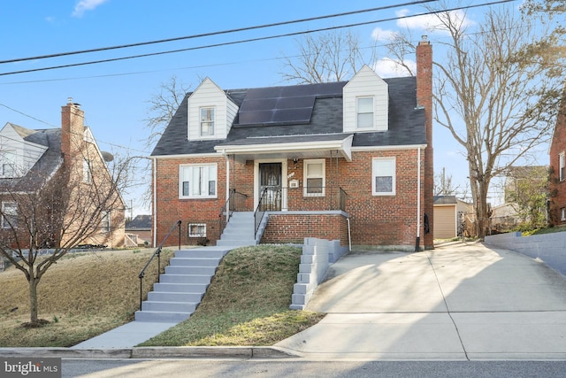 view of front of house with brick siding, solar panels, a chimney, and a shingled roof