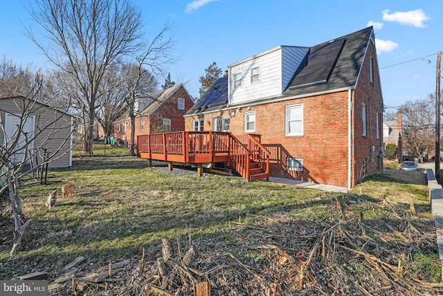 rear view of property featuring a lawn, brick siding, and a wooden deck