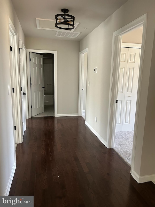 hall with dark wood finished floors, visible vents, and baseboards