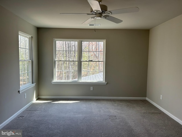 spare room with a ceiling fan, carpet flooring, visible vents, and baseboards