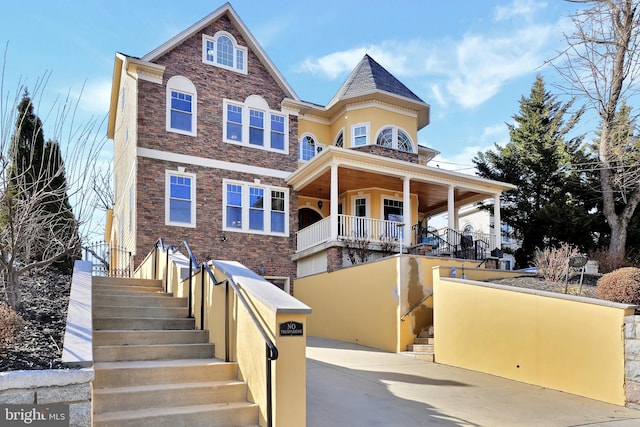 view of front of house featuring concrete driveway, stairway, and stone siding