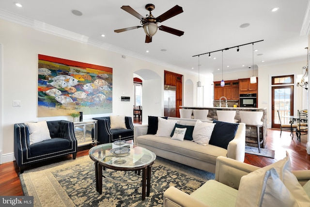 living room featuring arched walkways, crown molding, dark wood finished floors, recessed lighting, and ceiling fan with notable chandelier