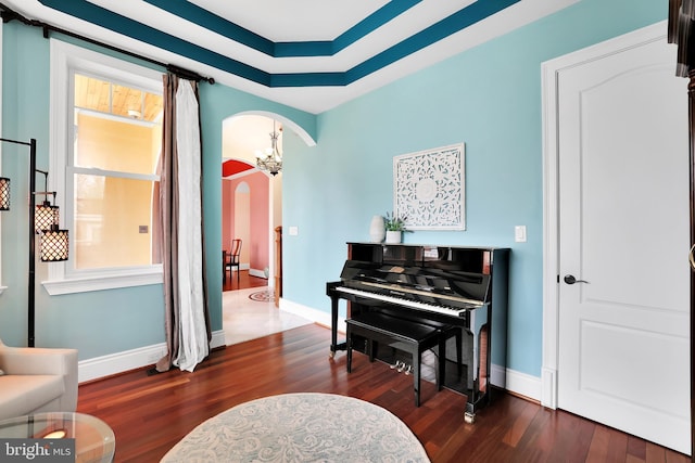 sitting room with arched walkways, a notable chandelier, dark wood finished floors, and baseboards