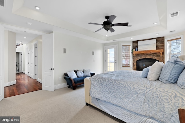 bedroom featuring baseboards, visible vents, a raised ceiling, carpet, and a fireplace