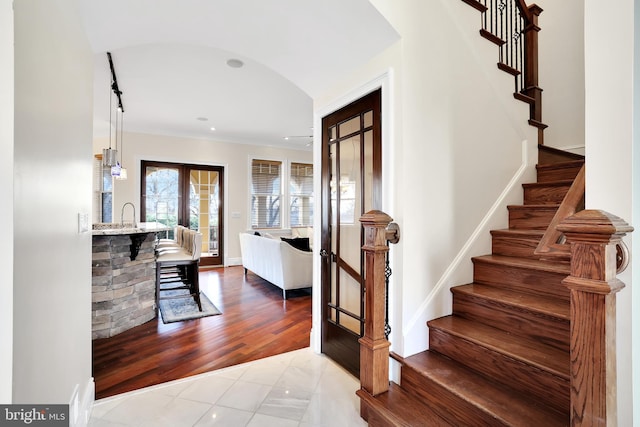 foyer entrance featuring arched walkways, wood finished floors, baseboards, french doors, and stairway