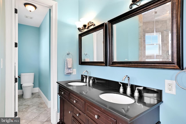 bathroom with double vanity, baseboards, toilet, and a sink