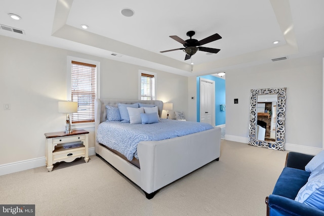 bedroom with carpet floors, visible vents, and a tray ceiling