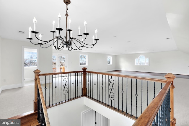 staircase featuring a notable chandelier, baseboards, visible vents, and a wealth of natural light