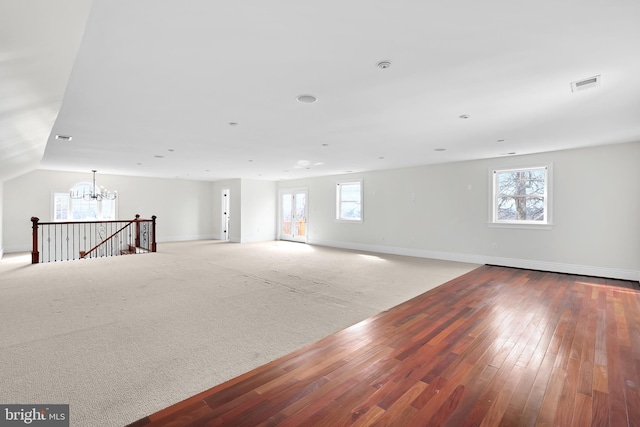 unfurnished room with baseboards, visible vents, wood finished floors, carpet floors, and a notable chandelier