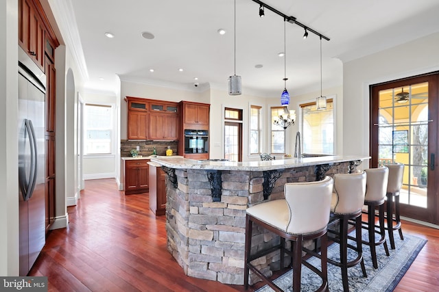 kitchen featuring decorative backsplash, dark wood finished floors, a breakfast bar, oven, and stainless steel built in refrigerator