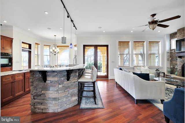 kitchen featuring plenty of natural light, open floor plan, dark wood-type flooring, light stone countertops, and black oven