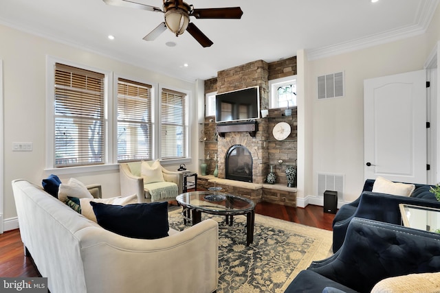 living area with crown molding, visible vents, a fireplace, and wood finished floors